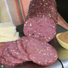 two salamis, cheese and sauce are on a metal surface next to a plate