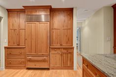 an empty kitchen with wooden cabinets and granite counter tops, along with hardwood flooring