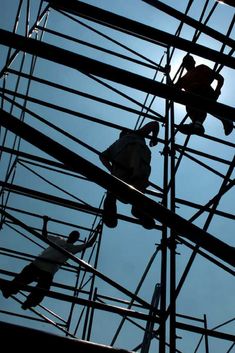 two people are climbing high up on the power lines in an electrical area with blue sky behind them