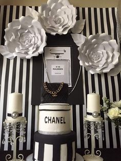 there is a chanel cake with flowers and candles on the table next to it