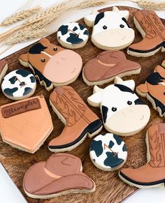 decorated cookies in the shape of cowboy boots and cow shoes on a wooden platter