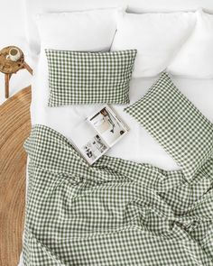 a bed with green gingham comforter and white pillows on top of it