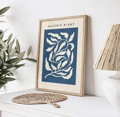 a white shelf with a blue and white art print on it next to a potted plant