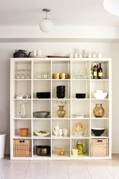 a white bookcase filled with lots of dishes and cups on top of it's shelves