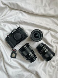 three cameras sitting next to each other on a white sheet with a camera lens in the foreground