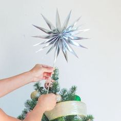 a woman is decorating a christmas tree with silver star decorations on the top and bottom