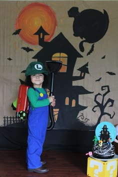 a little boy dressed up as luigi from mario kart and holding a broom in front of a halloween backdrop