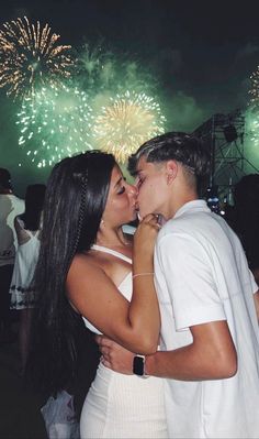 a man and woman kissing in front of fireworks