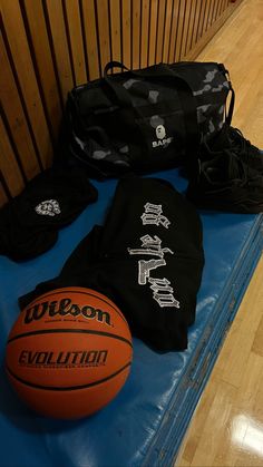 an orange basketball sitting on top of a blue mat next to other sports gear and accessories