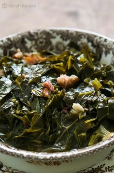 a bowl filled with greens and bacon on top of a table