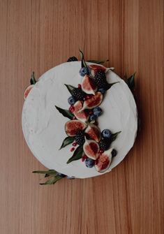 a white cake topped with fruit and leaves