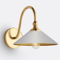 a brass wall light with a white shade