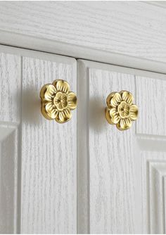 two golden knobs on the front of a white cabinet door with woodgrain