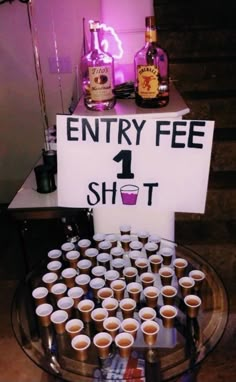 there is a sign that says entry fee 1 shot on the table with cups in front of it