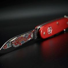 a red and black pocket knife sitting on top of a table