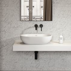 a white sink sitting under a bathroom mirror next to a wall mounted faucet