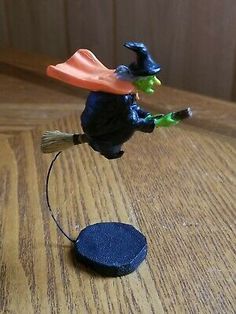 a small figurine on a wooden table with a broom and witch's hat