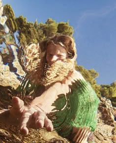 a man with long hair and beard sitting on the ground in front of some water