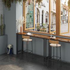 two bar stools sitting next to each other in front of an open window with potted plants