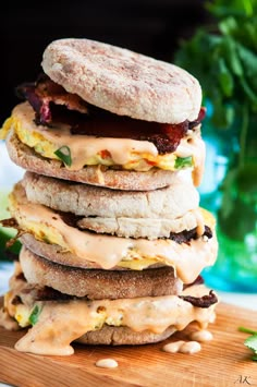 a stack of food sitting on top of a wooden cutting board next to a green plant