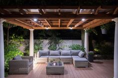 an outdoor living area with couches, tables and lights on the patio at night