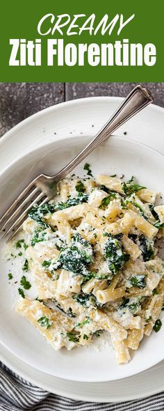 a white plate topped with pasta covered in cheese and spinach next to a fork