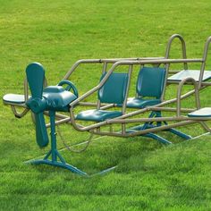 three blue seats are attached to a metal structure in the middle of a grassy field