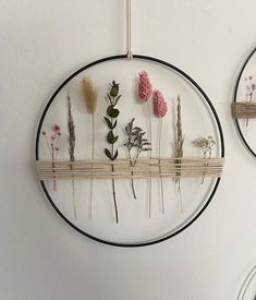 two circular wall hangings with flowers on them and plants in the middle one is made out of wire