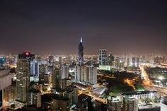 the city is lit up at night with skyscrapers in the foreground and other tall buildings