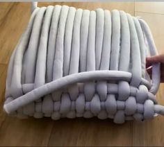 a person is holding an object made out of white plastic tubes on the wooden floor