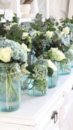 several mason jars filled with flowers and greenery