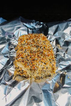 a piece of food sitting on top of foil covered in seasoning sprinkles