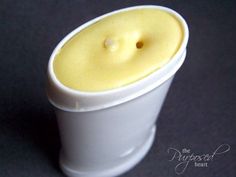 a small white cup with a yellow candle inside