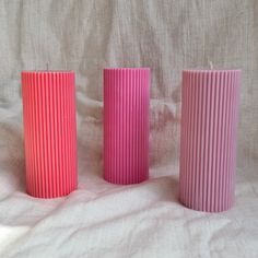 three pink candles sitting on top of a white sheet