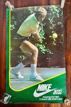 a tennis player is hitting the ball with his racket on a wooden table in front of a green and white poster