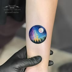 a person with a tattoo on their arm is holding up a small circular sticker