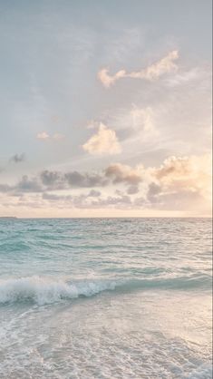 the sun is setting over the ocean with waves crashing on the shore and clouds in the sky