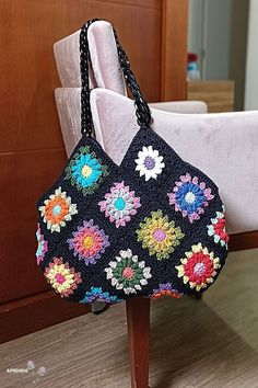 a crocheted purse sitting on top of a wooden table next to a white chair