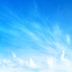 an airplane flying in the blue sky with white clouds