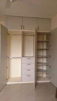 an empty room with white closets and drawers in it's center, next to a ceiling fan