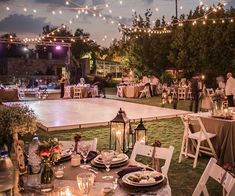 an outdoor event with tables and chairs set up for dinner, lit by string lights