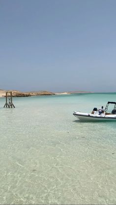 a small boat is in the clear blue water near a dock on an island off the coast