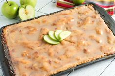 an apple cake with caramel icing and sliced apples on the table next to it