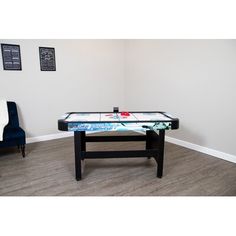 an air hockey table in the corner of a room with chairs and pictures on the wall