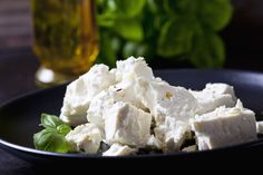 a black plate topped with feta cheese and basil