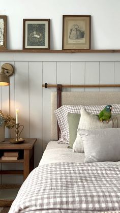 a bed with white and grey checkered bedspread next to three framed pictures on the wall