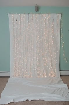 a white curtain with lights hanging from it's side in front of a blue wall