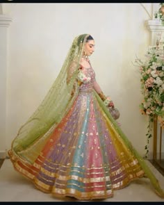 a woman in a colorful wedding dress standing next to a vase with flowers on it