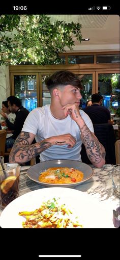 a man sitting at a table in front of a plate of food with his hands on his face