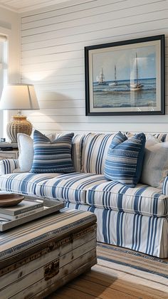 a blue and white striped couch in a living room next to a table with a lamp on it